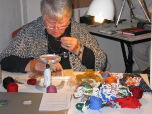 Jackie Wollenberg using a magnifier to see the fine detail in her tapestries.